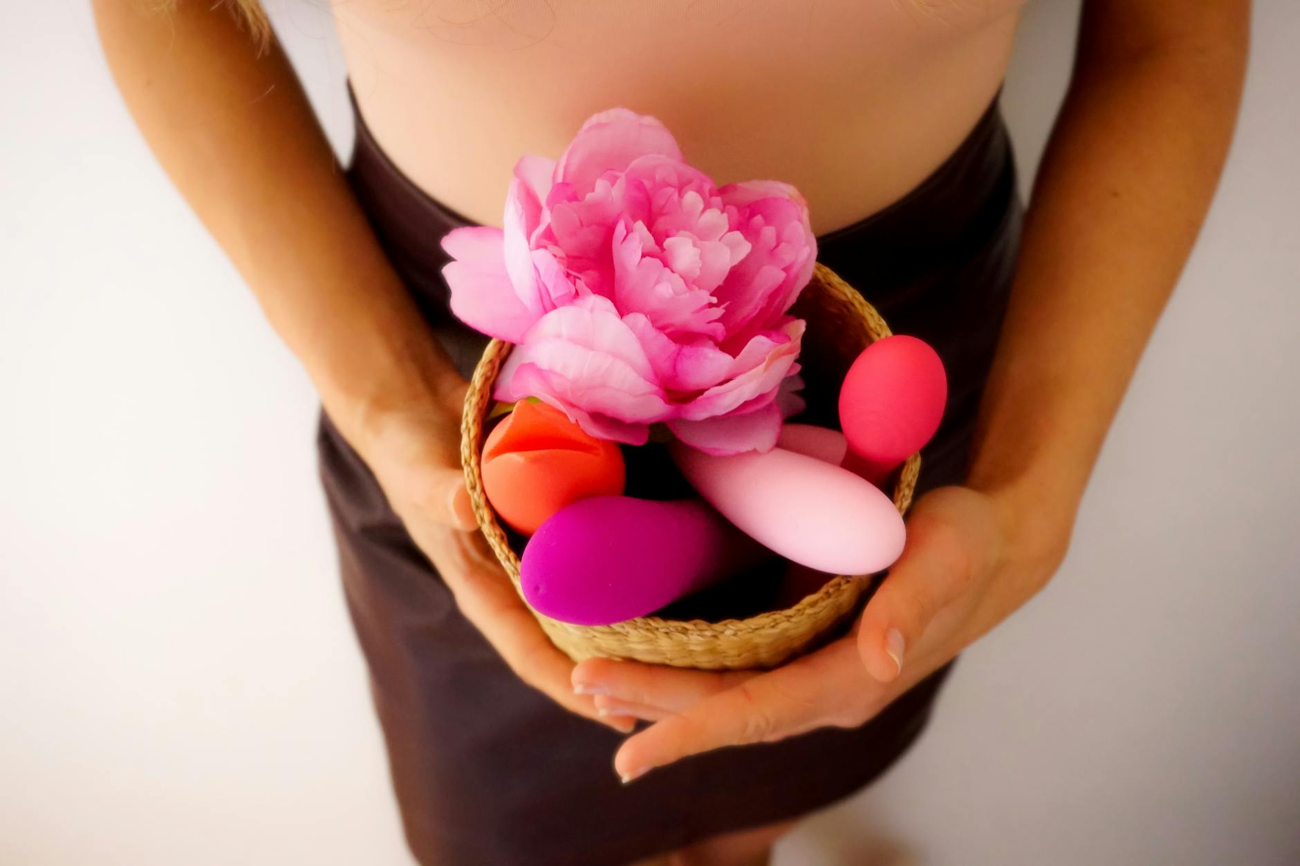 Hands holding pastel-colored silicone toys for intimate wellness